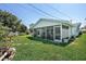 View of a screen enclosed porch in a backyard with lush green grass and landscaped yard at 5053 43Rd S St, St Petersburg, FL 33711
