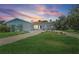 Charming home with a well-manicured lawn, circular driveway, and delightful landscaping under a colorful sunset at 5053 43Rd S St, St Petersburg, FL 33711