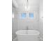 Bright bathroom featuring a standalone tub, two windows, and marble tiling from floor to ceiling at 5142 W San Jose St, Tampa, FL 33629
