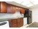 Functional kitchen with dark wood cabinets, granite countertops, and black refrigerator at 5421 Orange Blossom N Rd, Pinellas Park, FL 33782