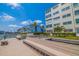 Community dock featuring bench seating and views of the condo building, waterway, and palms at 5575 Gulf Blvd # 329, St Pete Beach, FL 33706