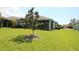 The home features a beautiful backyard with a screened-in porch, lush green grass, and a beautiful tree at 6417 Blue Sail Ln, Apollo Beach, FL 33572