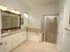 Bright bathroom with a double vanity, large mirror, soaking tub, and glass-enclosed shower at 6417 Blue Sail Ln, Apollo Beach, FL 33572