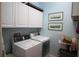 Functional laundry room equipped with a side-by-side washer and dryer and overhead cabinets at 6417 Blue Sail Ln, Apollo Beach, FL 33572
