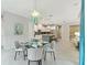 Open-concept dining area with glass table, stylish blue curtains, and views of the kitchen and living area at 716 Manns Harbor Dr, Apollo Beach, FL 33572