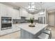 Bright kitchen features white cabinetry, stainless steel appliances, gray island with white countertop, and stylish pendant lighting at 716 Manns Harbor Dr, Apollo Beach, FL 33572