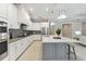 Bright and modern kitchen featuring white cabinets, stainless steel appliances, gray island with a white countertop at 716 Manns Harbor Dr, Apollo Beach, FL 33572