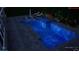 An in-ground pool at night with a spa, blue lights and pavers all around at 716 Manns Harbor Dr, Apollo Beach, FL 33572
