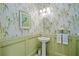 Charming powder room showcasing vibrant wallpaper, wainscoting, and a pedestal sink at 716 Manns Harbor Dr, Apollo Beach, FL 33572