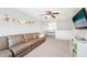 Cozy upstairs living room with a brown couch, TV, ceiling fan, and natural light at 7207 Forest Mere Dr, Riverview, FL 33578