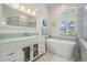 Bright bathroom featuring a soaking tub, glass shower, and white vanity with a glass countertop at 10510 Castleford Way, Tampa, FL 33626