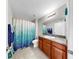 Bathroom with a single vanity, wood cabinetry, granite countertops, and a stylish shower curtain at 11208 Leland Groves Dr, Riverview, FL 33579