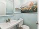 Powder room with blue walls, white trim, and artistic floral accent wall at 11383 Pickford St, Spring Hill, FL 34609