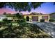 Charming single-story home with a three car garage and mature landscaping at dusk at 11383 Pickford St, Spring Hill, FL 34609