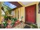 Inviting front porch with decorative red door, lush tropical plants, and stone accents at 11383 Pickford St, Spring Hill, FL 34609