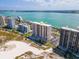 An aerial view of a beachfront condo shows a community pool with nearby tennis courts at 1270 Gulf Blvd # 1904, Clearwater Beach, FL 33767