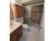 Well-lit bathroom featuring a glass-enclosed shower, wood cabinets, and neutral tile flooring at 12809 Wedgewood Way # A, Hudson, FL 34667