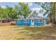 Charming blue home with stone accents, well-maintained lawn and mature trees at 1513 Escort Ave, Tampa, FL 33610