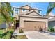 Two-story home featuring a two-car garage, stone accents and tropical landscaping at 16717 Myrtle Sand Dr, Wimauma, FL 33598