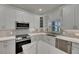 Close-up of kitchen features white cabinets, stainless steel appliances, and quartz countertops at 1806 Mira Lago Cir, Ruskin, FL 33570