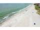 Aerial view of a long white sand beach with waves and buildings in the distance at 18102 2Nd St E, Redington Shores, FL 33708