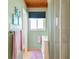 Bathroom features a window, vanity with towel and cabinet, wood plank ceiling, tile floor, and mint colored walls at 18102 2Nd St E, Redington Shores, FL 33708