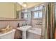 Bathroom features a combination shower/tub with beige tiling, pedestal sink, mirrored medicine cabinet, and toilet at 18102 2Nd St E, Redington Shores, FL 33708