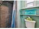 Bathroom showing tiled shower, toilet, shelving with decor, and mint colored walls at 18102 2Nd St E, Redington Shores, FL 33708