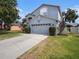 Exterior view of a blue two-story home with a gray garage door and landscaped front yard at 1830 Citrus Orchard Way, Valrico, FL 33594