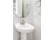 Bathroom featuring a pedestal sink, oval mirror, and brushed nickel fixtures at 19153 Elsimont Isle, Lutz, FL 33558