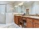 Bathroom featuring double sinks, granite countertop, walk-in shower with glass door, and vanity seating at 19337 Weymouth Dr, Land O Lakes, FL 34638