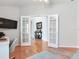 Open bonus room with hardwood floors, french doors, and view into the front foyer at 19337 Weymouth Dr, Land O Lakes, FL 34638