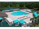 Aerial view of a community pool with sunshades, lounge chairs, and tennis courts in the background at 19337 Weymouth Dr, Land O Lakes, FL 34638