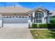 Charming home featuring a well-maintained lawn, a two-car garage, and a decorative arched window at 19337 Weymouth Dr, Land O Lakes, FL 34638