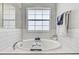 Close-up of a white tile bathtub featuring a chrome faucet and a clear window at 2190 Fairway S Ave, St Petersburg, FL 33712