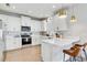 Modern kitchen with stainless steel appliances, white cabinetry, quartz countertops and stylish bar seating with brass pendant lighting at 2190 Fairway S Ave, St Petersburg, FL 33712