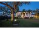 Expansive backyard features lush green lawn, mature trees, and elegant exterior lighting illuminating the home at 2501 S Dundee St, Tampa, FL 33629