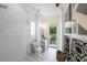 Well-lit bathroom featuring a glass shower, marble floors, and a view of the outdoor greenery at 2501 S Dundee St, Tampa, FL 33629