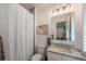 Cozy bathroom featuring a shower with curtain, toilet, vanity, and decorative mirror at 2501 S Dundee St, Tampa, FL 33629