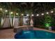 Captivating pool with a tile waterfall, serene lighting, and lush landscaping for a tranquil retreat at 2501 S Dundee St, Tampa, FL 33629