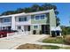 Townhouse with a light green exterior, white trim, a well kept front yard, and a gray roof at 2751 S Pines Dr # 10, Largo, FL 33771