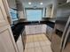 Modern kitchen with white cabinetry, black countertops, stainless steel appliances, and tile floors at 2751 S Pines Dr # 10, Largo, FL 33771