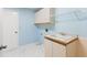 Practical laundry room with white tile flooring, utility sink, and ample storage cabinets at 3014 Ashland Ter, Clearwater, FL 33761