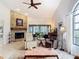 Cozy living room with fireplace, ceiling fan, and garden view at 3182 Windmoor N Dr, Palm Harbor, FL 34685