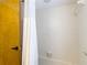 Bright shower area with white tiled walls and clear shower curtain next to a wood door at 3182 Windmoor N Dr, Palm Harbor, FL 34685
