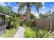 Landscaped backyard featuring a stone pathway, vibrant plants, and a wooden fence for privacy at 4105 W Bay Villa Ave, Tampa, FL 33611