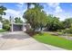 Property features a driveway leading to a carport, surrounded by green lawn, trees and a glimpse of the home at 4105 W Bay Villa Ave, Tampa, FL 33611