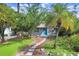Inviting home featuring a stone pathway leading to a bright blue door, surrounded by lush greenery and a palm tree at 4105 W Bay Villa Ave, Tampa, FL 33611