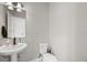 Cozy half bathroom with pedestal sink and standard toilet, illuminated by modern vanity lighting at 5501 N 15Th St, Tampa, FL 33610