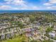 Wide aerial view of neighborhood homes, lush trees, open green space and blue sky backdrop at 879 De Soto Blvd, Tarpon Springs, FL 34689